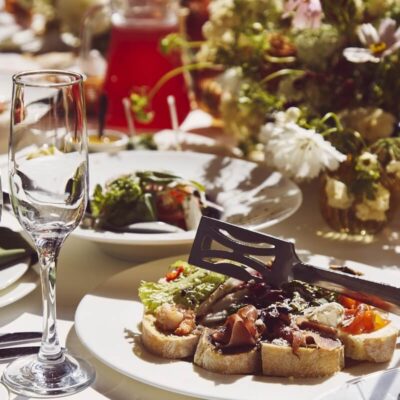 Elegancko przystrojony stół z daniami na talerzach to przykład, jak wygląda catering na imprezy okolicznościowe.