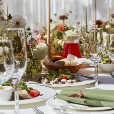 Elegancko nakryty stół z przekąskami, kieliszkami i kwiatami, idealny na catering na przyjęcia.