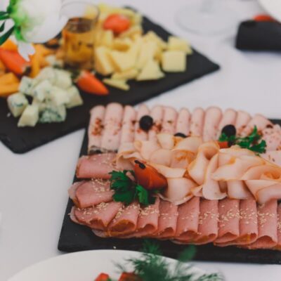 Tacki cateringowe z wędlinami i serami na eleganckim stole.
