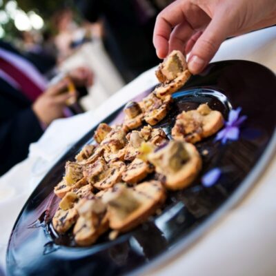 Ręka sięga po przekąskę z tacki cateringowej.