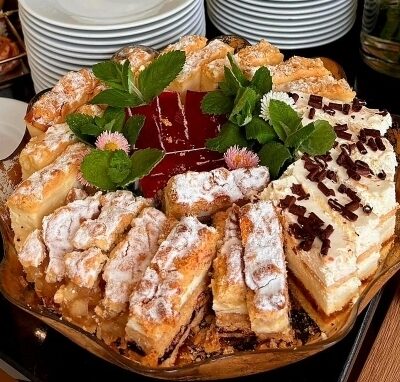 Catering na spotkania biznesowe obejmuje różnorodne ciasta pięknie podane na dużym talerzu.