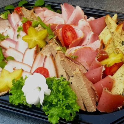 Tacki cateringowe z elegancko ułożonymi mięsami, warzywami i dekoracją.